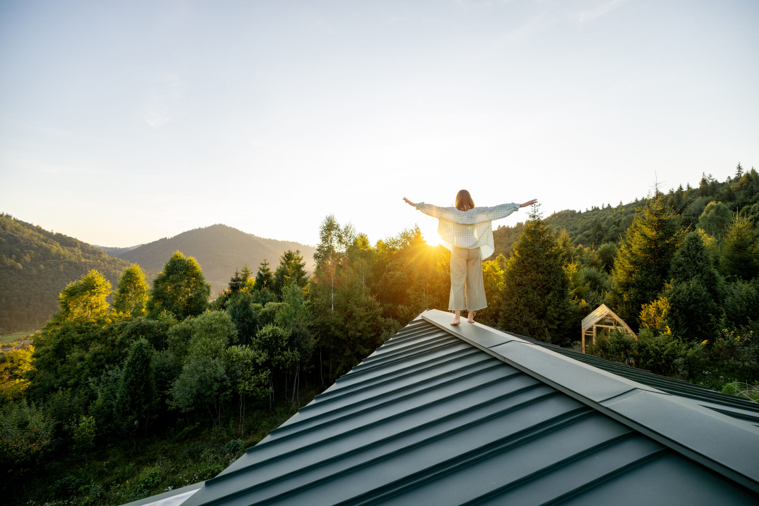 A woman walks on a rooftop as the sun rises over the mountains, embracing the peaceful solitude and beauty of nature. Perfect moment of calm and reflection