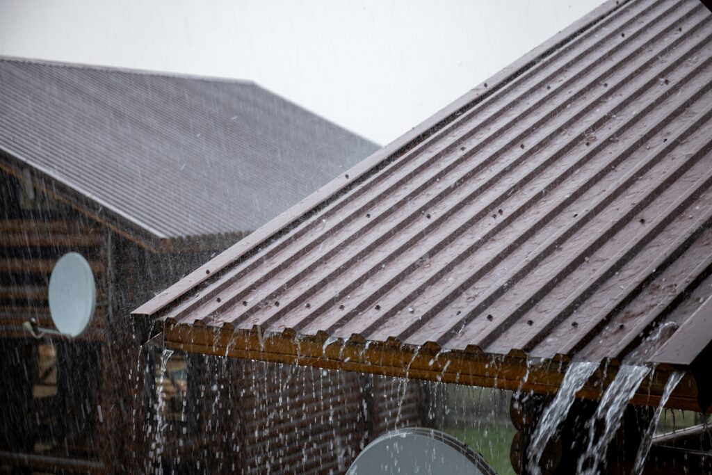 Pluie battante ruisselant sur des panneaux métalliques nervurés en gros plan — toit en métal et bruit de pluie.